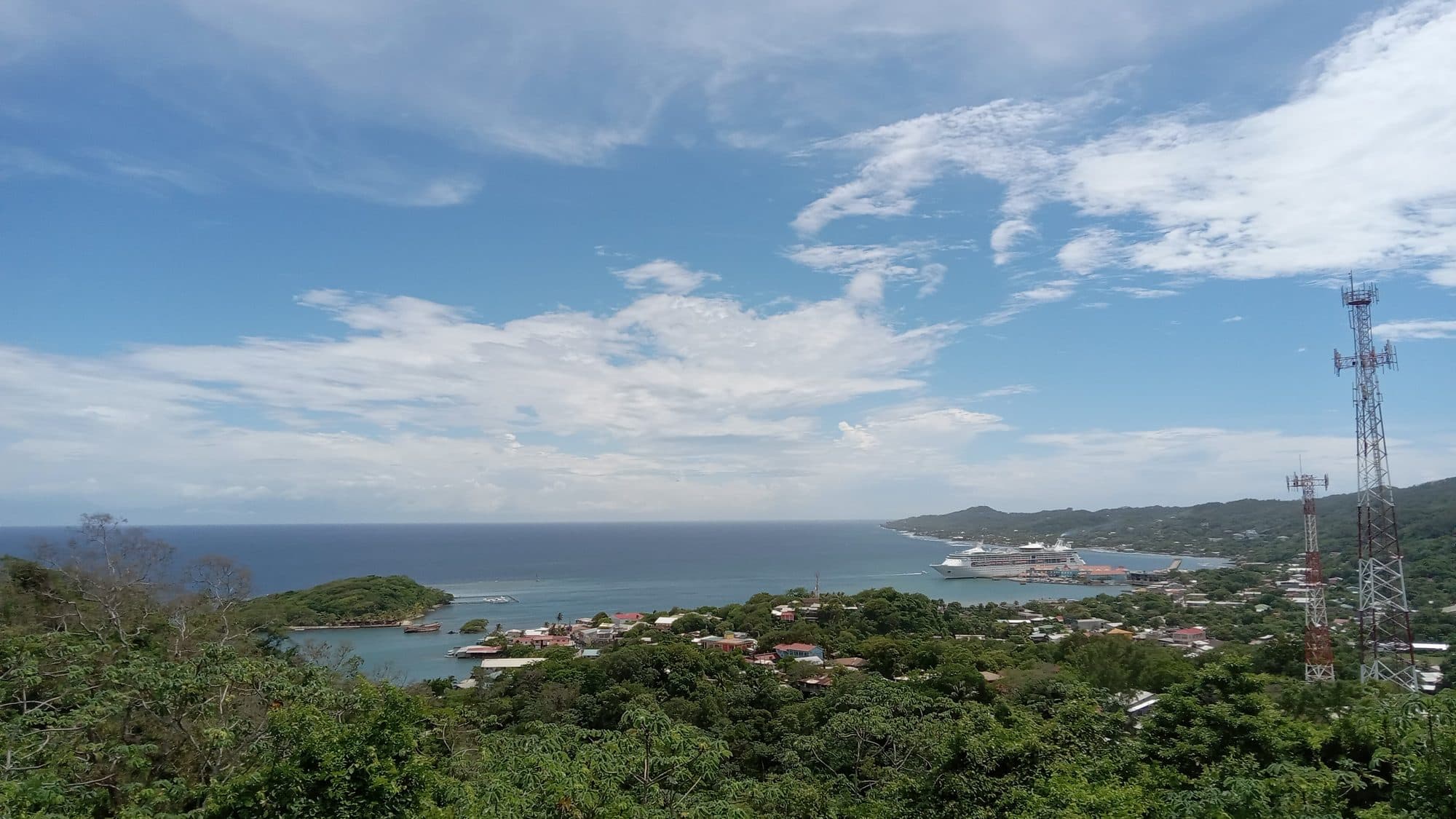 Vista desde lo alto sobre Coxen Hole con un crucero atracado en el puerto y el Caribe al fondo