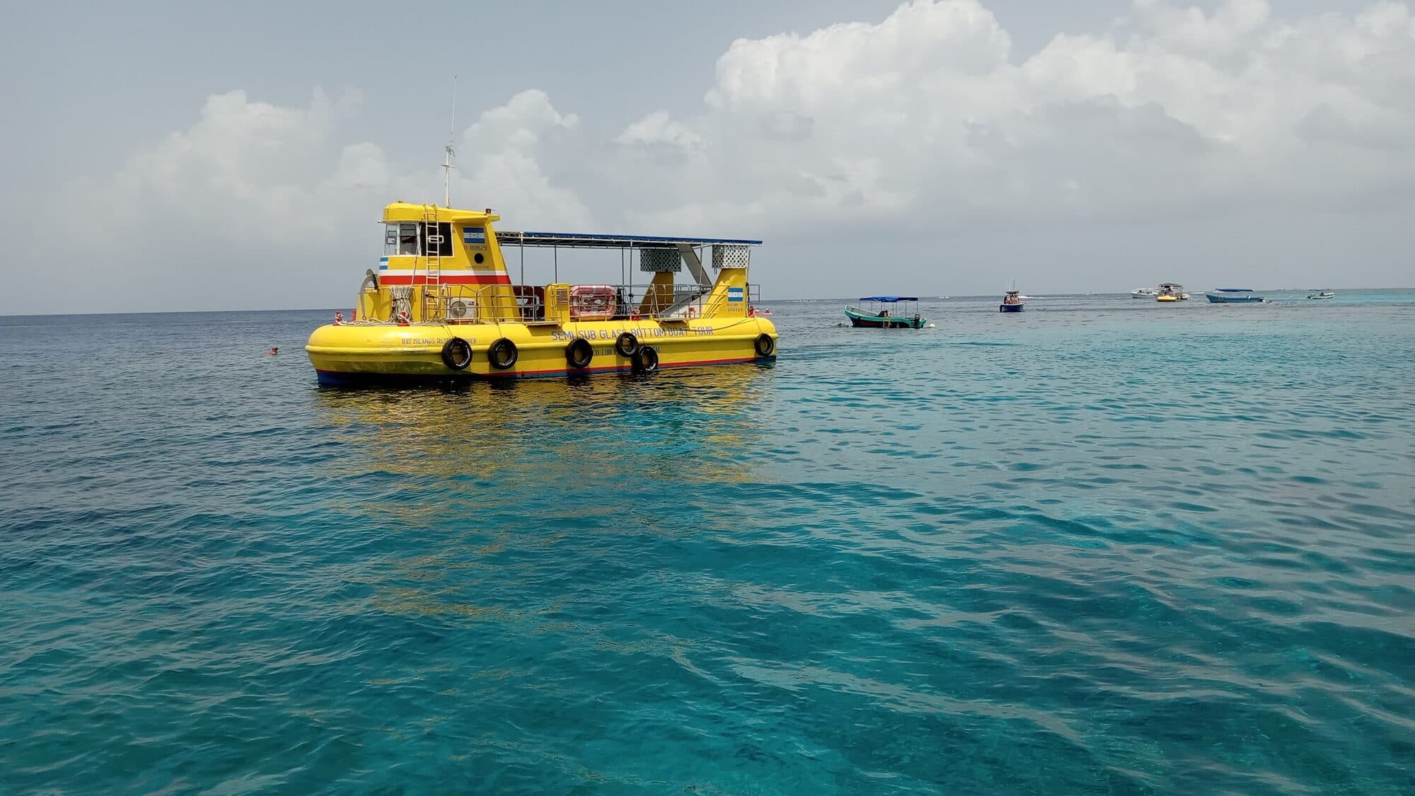 Un semisumergible amarillo con fondo de cristal fondeado sobre el arrecife en agua turquesa