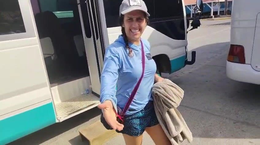 Una guía de Monkey Lala sonriendo junto a la puerta abierta de la van del tour en el puerto