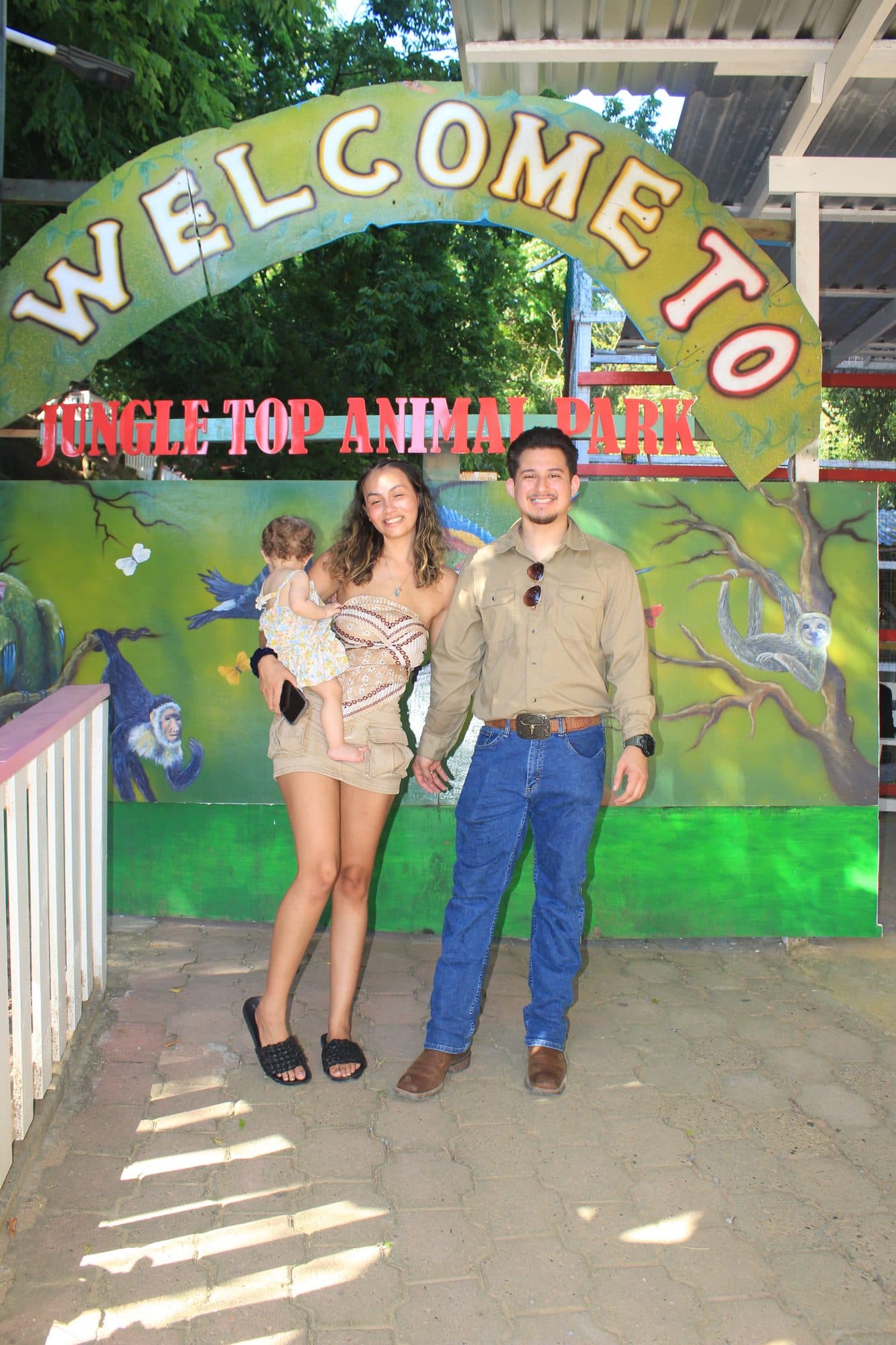 Una familia con un bebé en el arco pintado de entrada del Jungle Top Animal Park