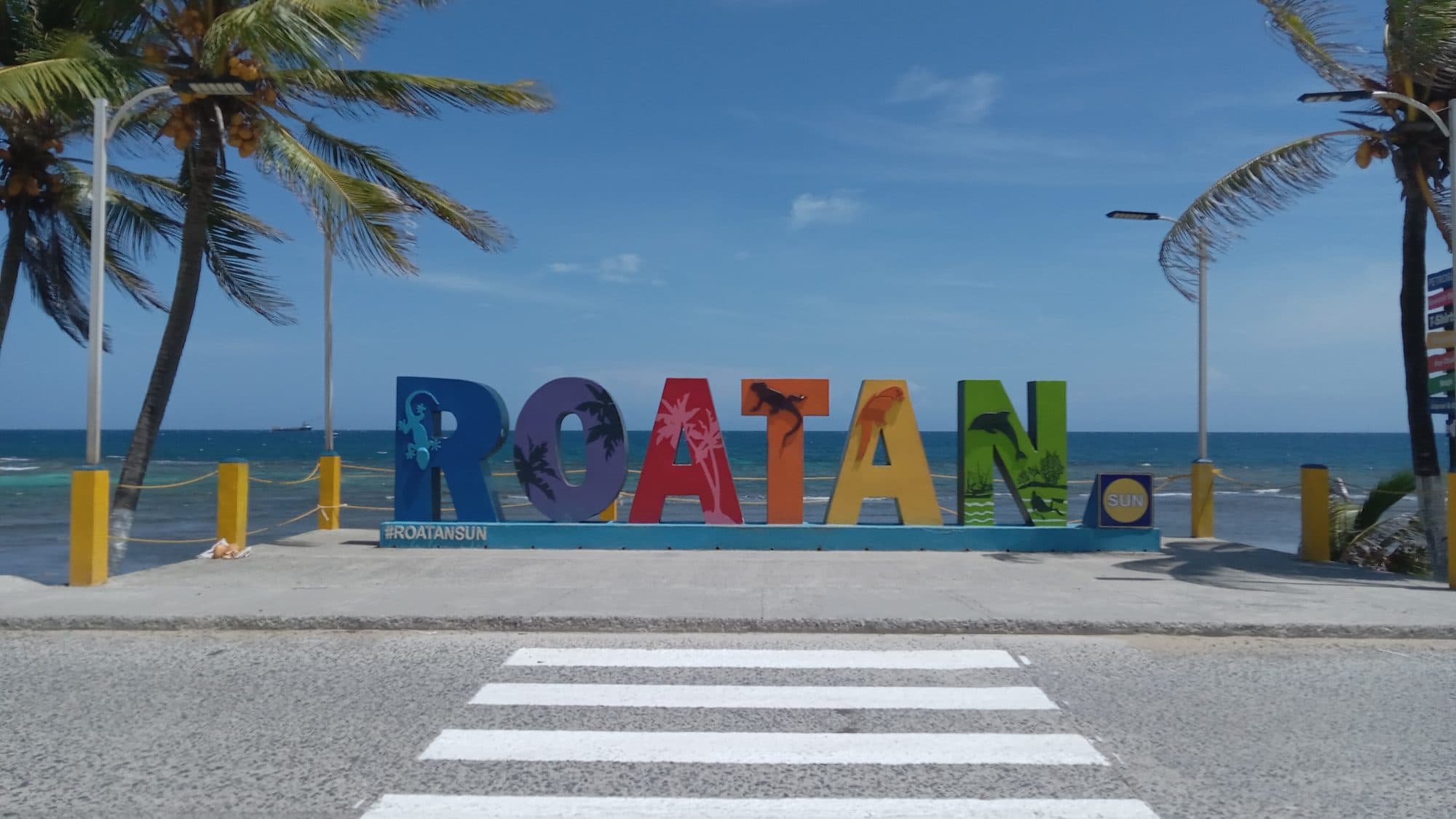 El rótulo de letras pintadas de ROATÁN frente al mar, cada letra de un color